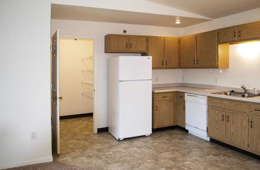 an empty kitchen with a white refrigerator and sink