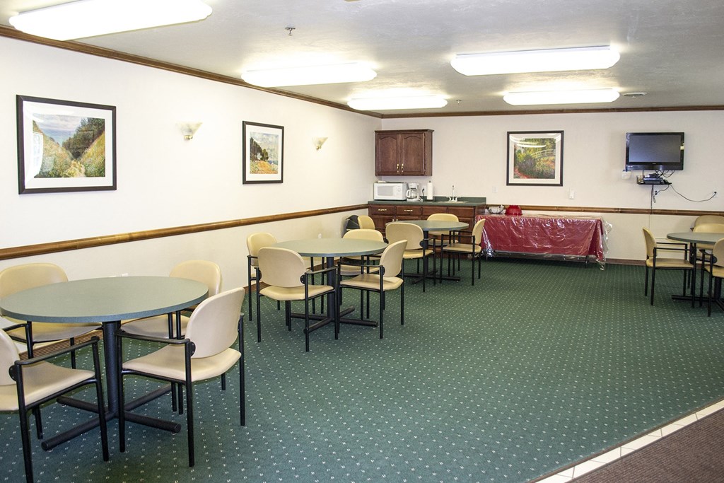 a dining room with tables and chairs and a kitchen in the background