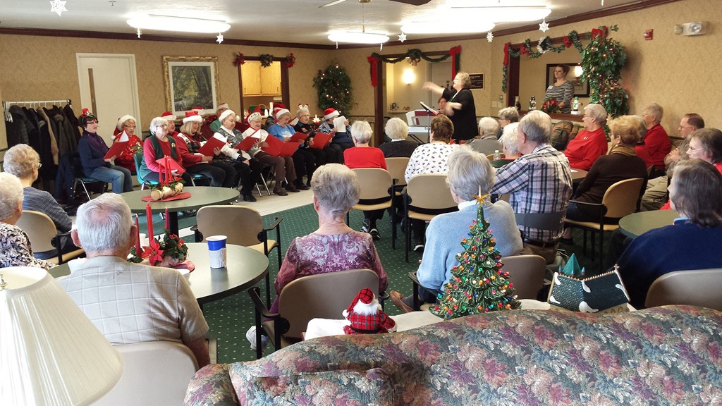 a large group of people sitting in a room with a christmas tree