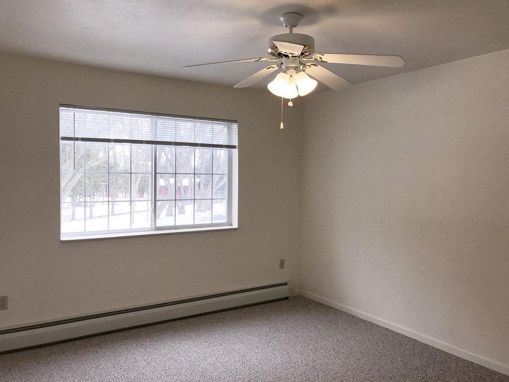 an empty bedroom with a ceiling fan and a window