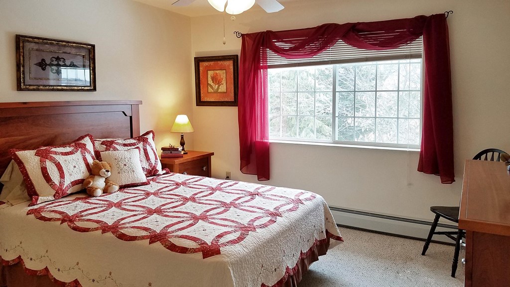 a bedroom with a bed and a window with red curtains
