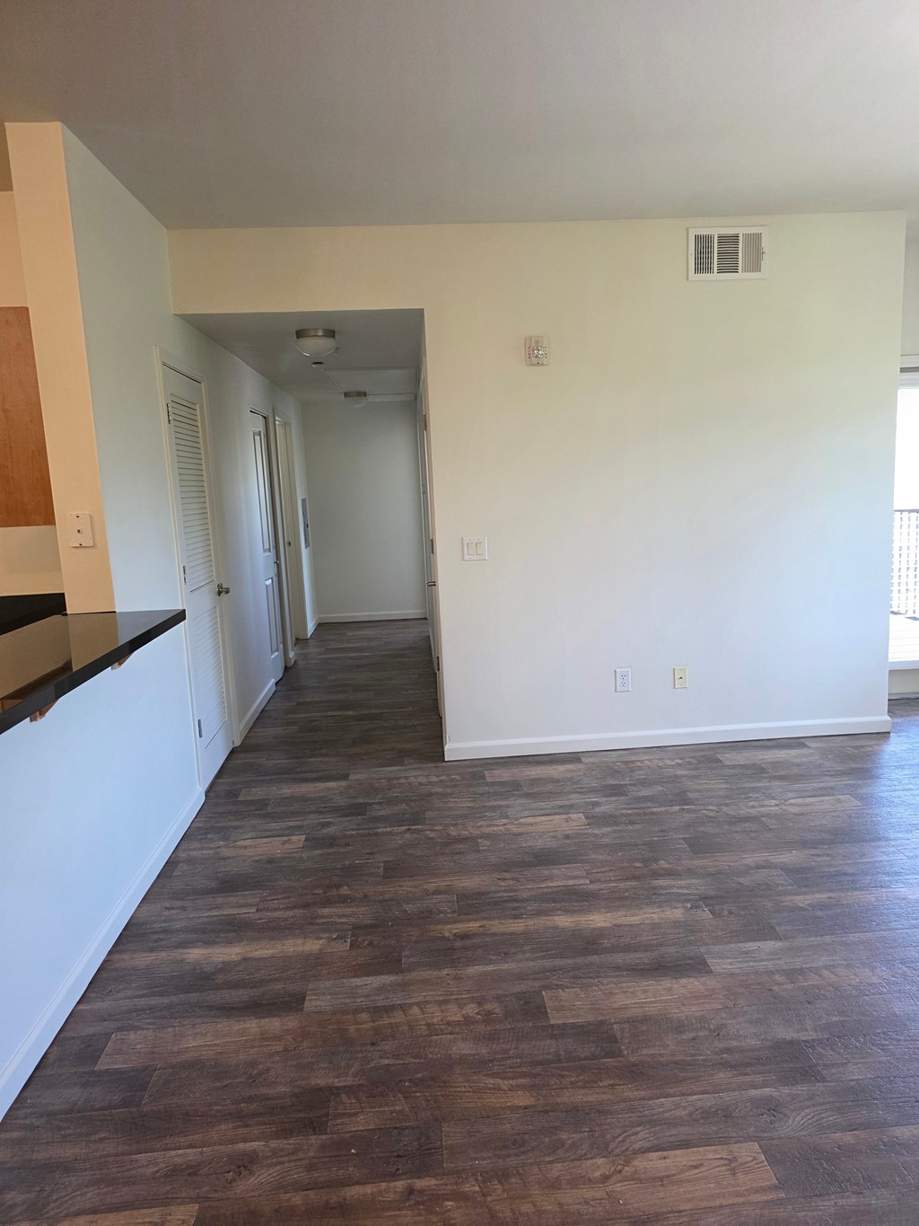 A long hallway with wood floors and white walls.