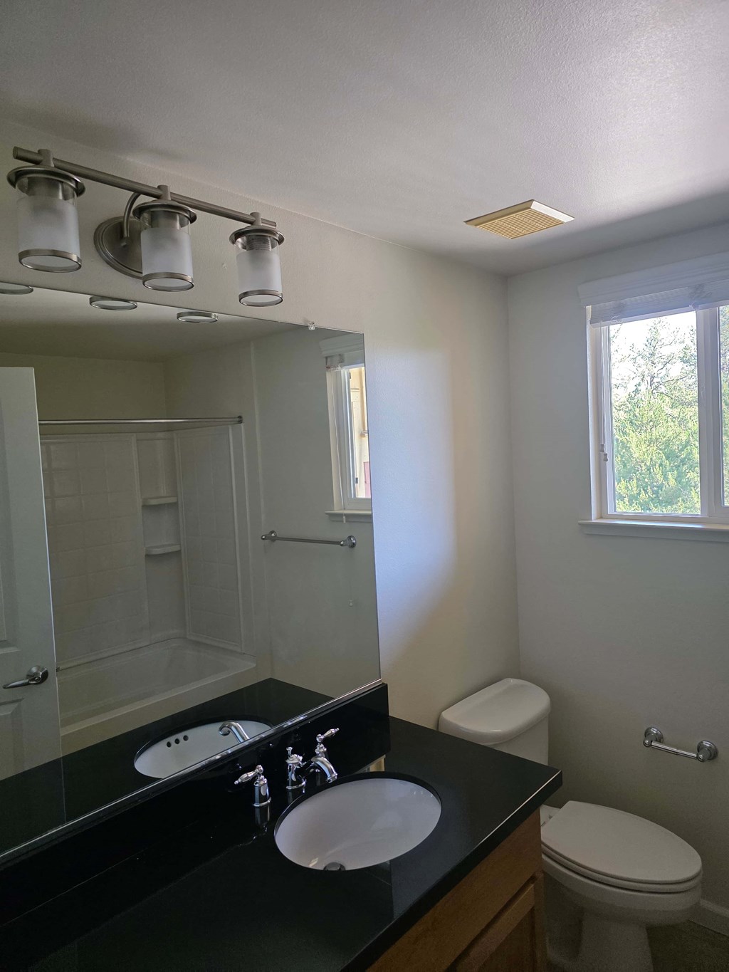 A bathroom with a sink, toilet, and mirror.