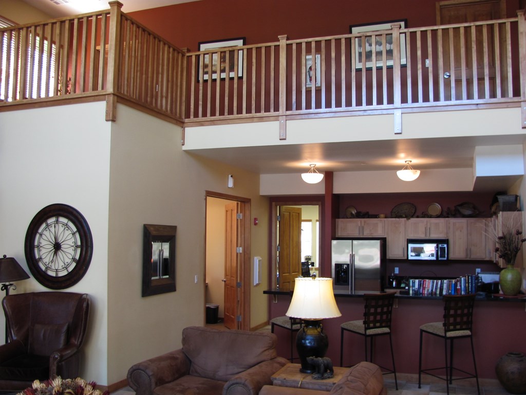A living room with a couch, chair, and a clock on the wall.