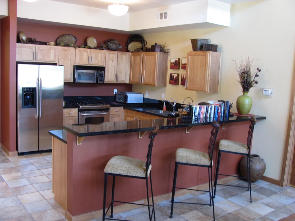 a kitchen with a bar and a stainless steel refrigerator