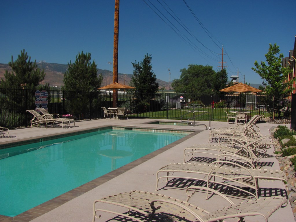 A pool surrounded by chairs and a fence.