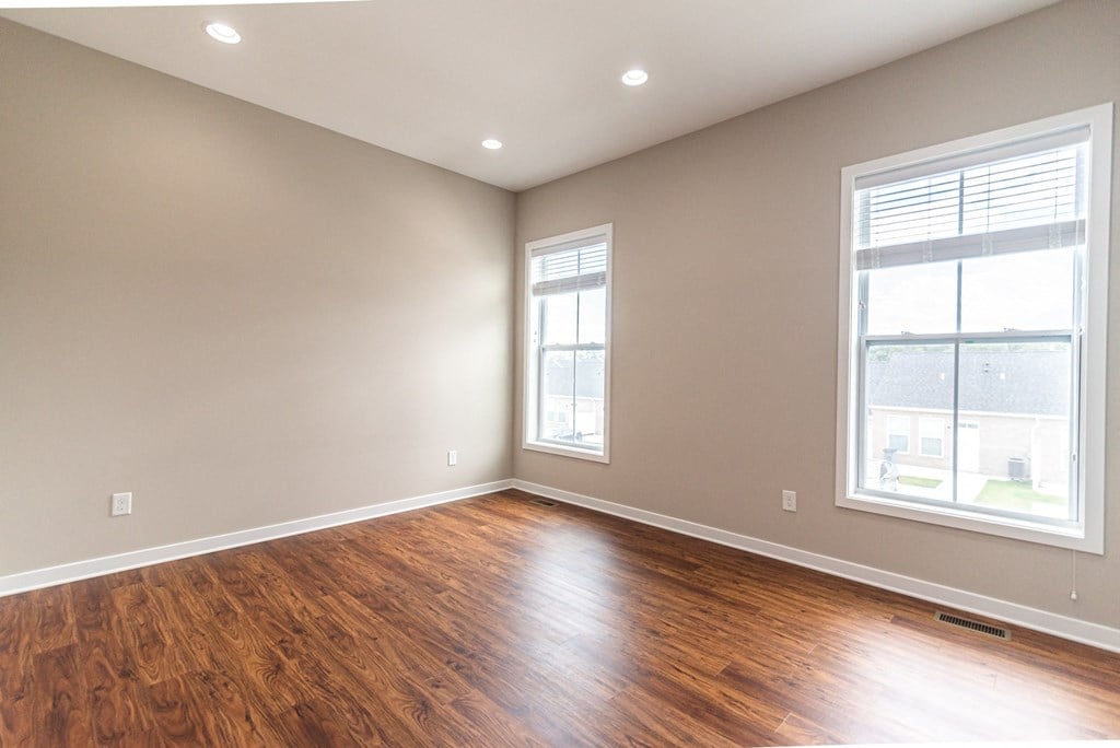 an empty living room with wood floors and two windows