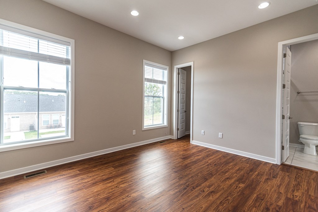 an empty living room with wood flooring and a bathroom