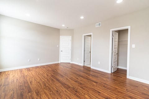 an empty living room with wood flooring and a closet