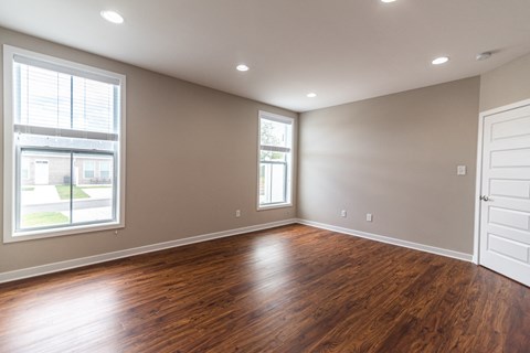 an empty living room with wood floors and a window