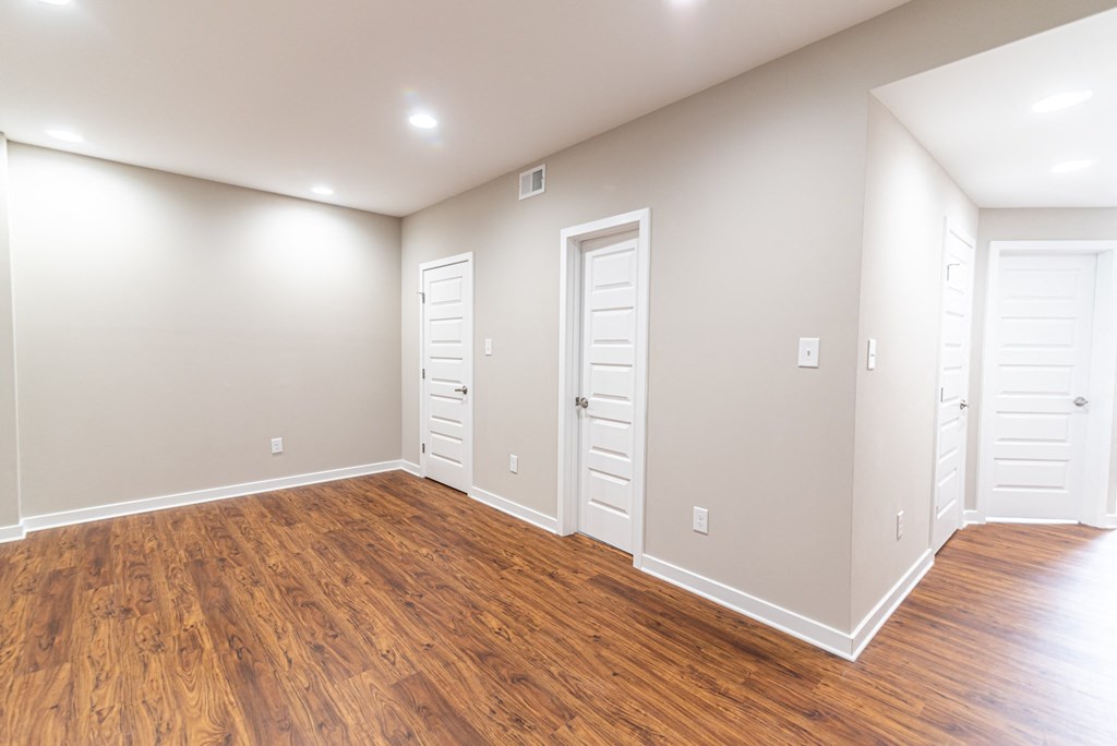 an empty living room with wood floors and white doors