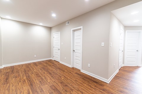 an empty living room with wood floors and white doors