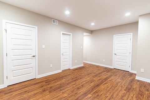 an empty room with two doors and a wood floor