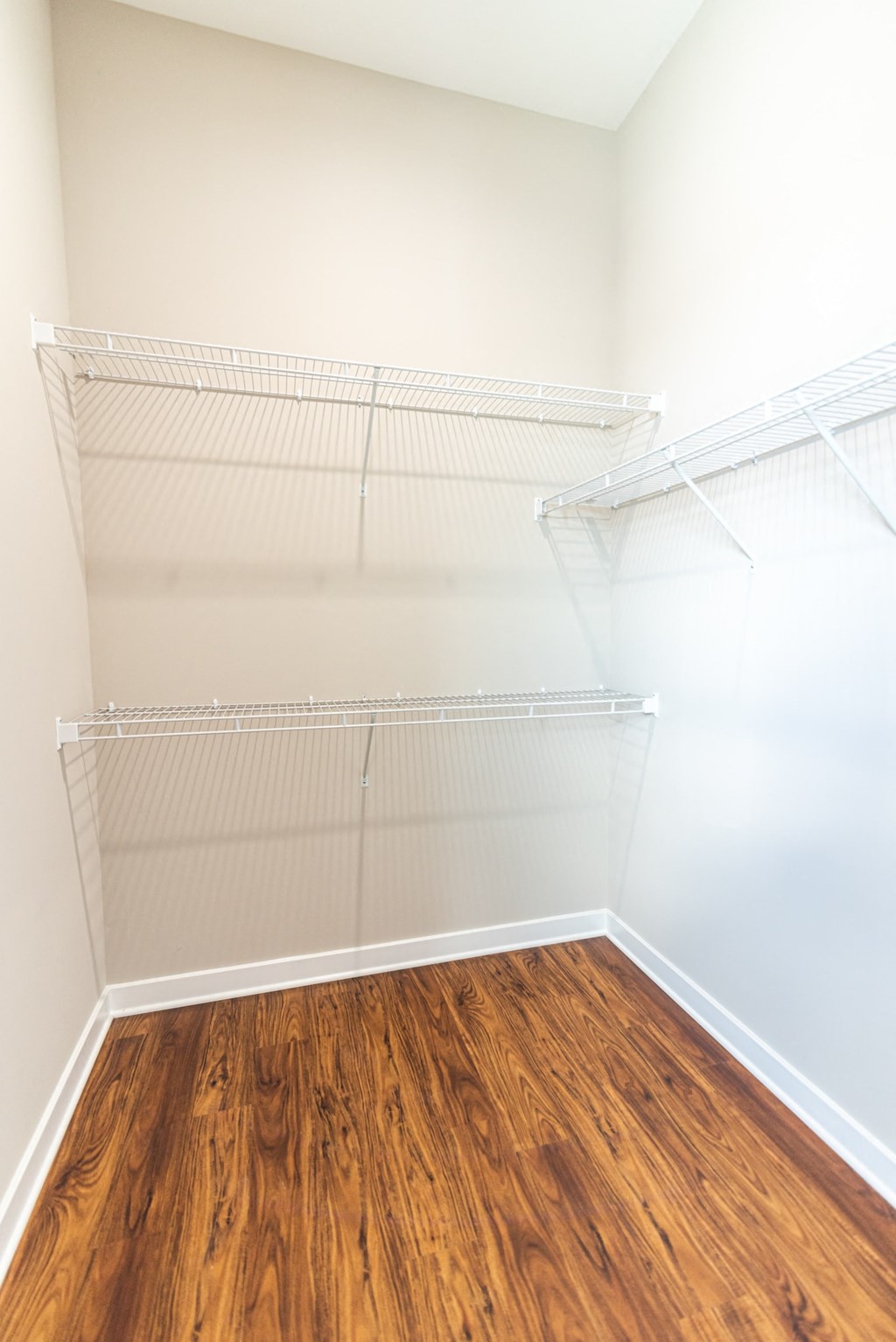 an empty closet with a wood floor in a room with white walls