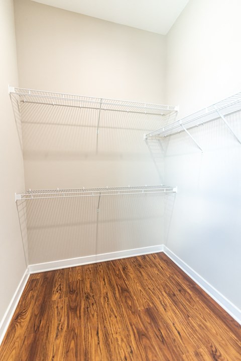 an empty closet with a wood floor in a room with white walls