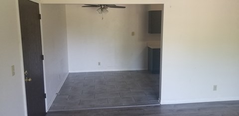 an empty living room with a ceiling fan and a tiled floor