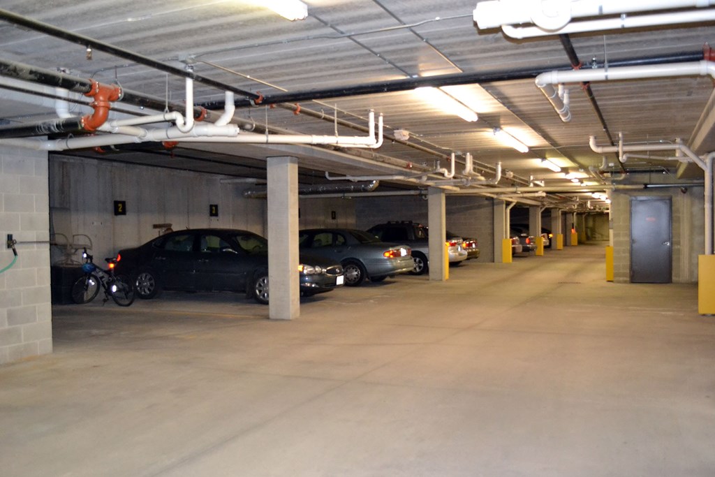 A parking garage with cars parked and a motorcycle.
