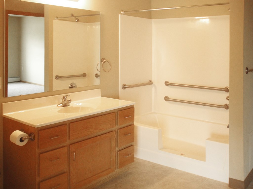 A bathroom with a sink, mirror, and shower.