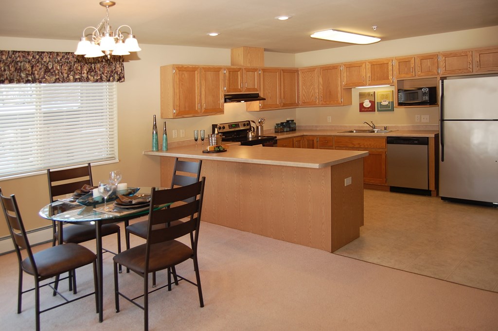 A kitchen with a table and chairs in front of it.