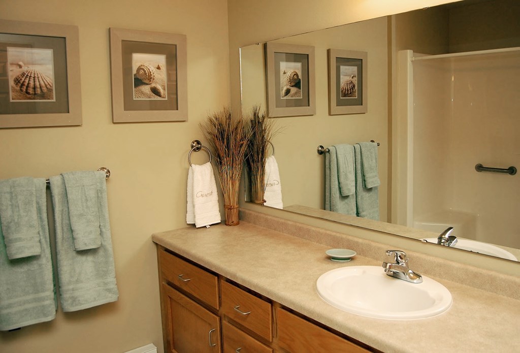 A bathroom with a sink, mirror, and towels.