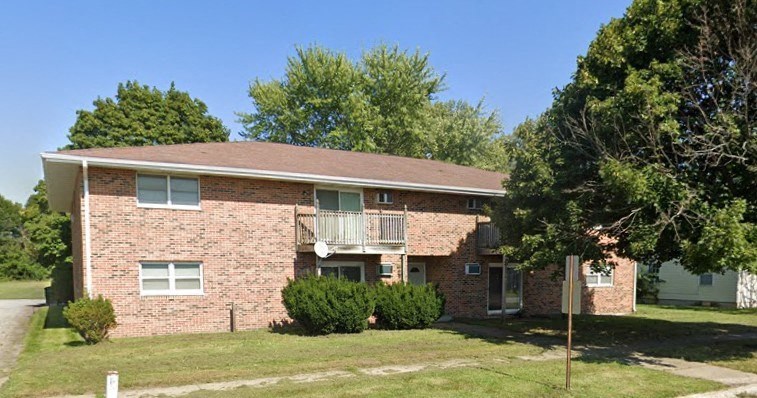 a brick house with a balcony on a lawn