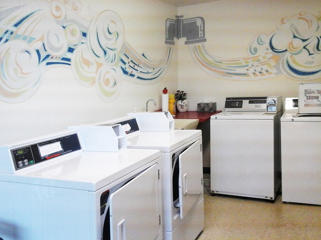 three washing machines and two refrigerators in a laundry room