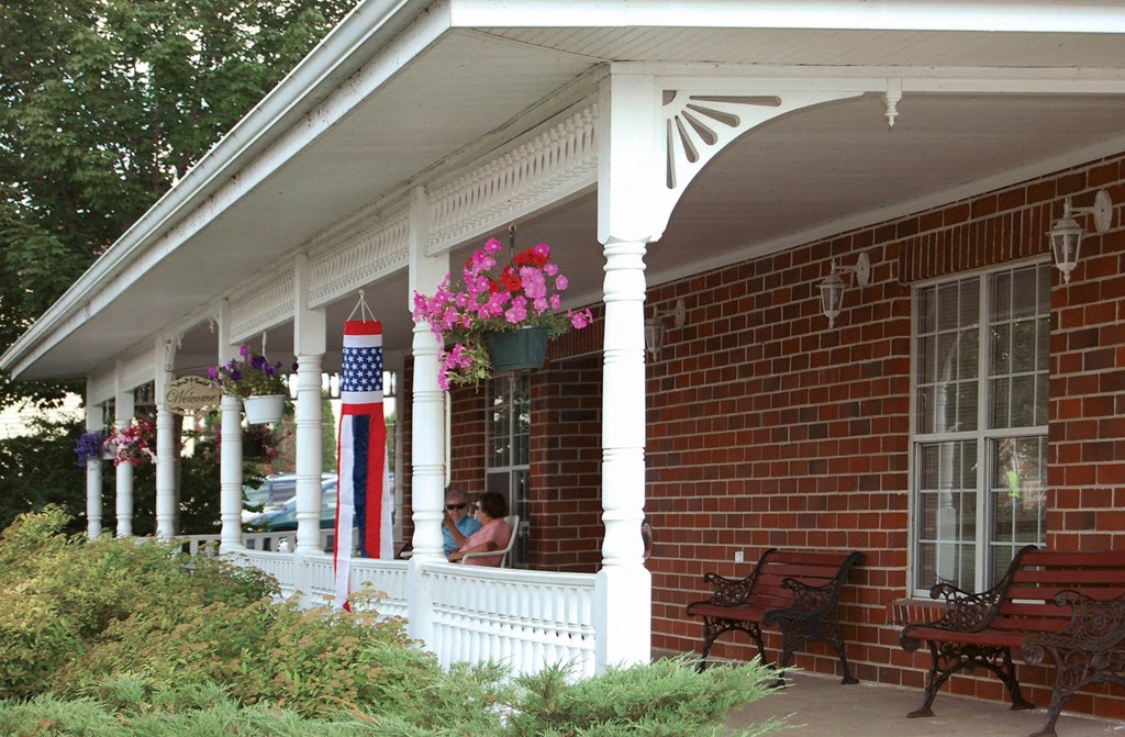 a woman sitting on the porch of a brick house