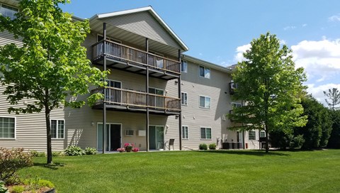 the view of a large apartment building with a lawn and trees