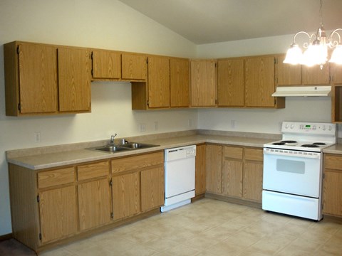 an empty kitchen with white appliances and wooden cabinets