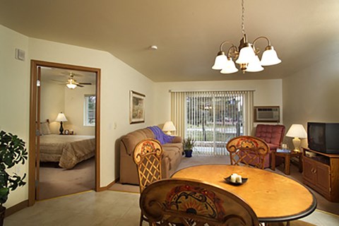 a living room with a dining table and a bedroom with a bed