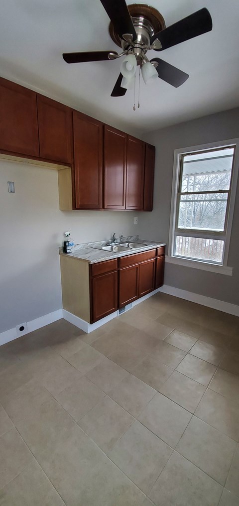 an empty kitchen with wooden cabinets and a ceiling fan