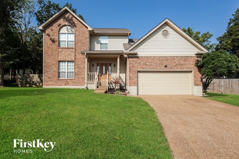 A house with a brown brick facade and a white garage door is for sale.