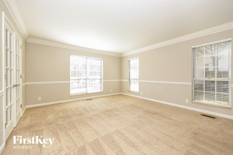 A room with a carpeted floor and two windows.