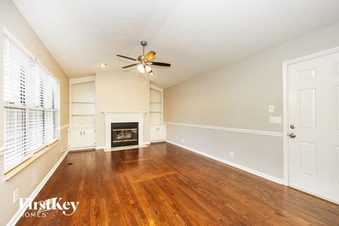 A spacious room with a fireplace and wooden floors.
