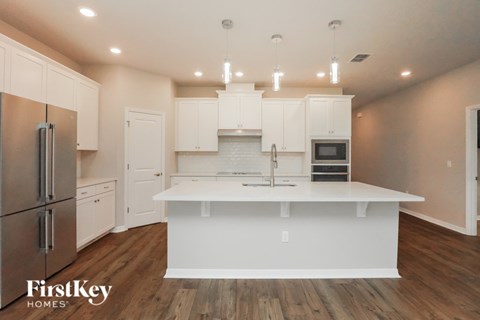 A kitchen with white cabinets and a wooden floor.