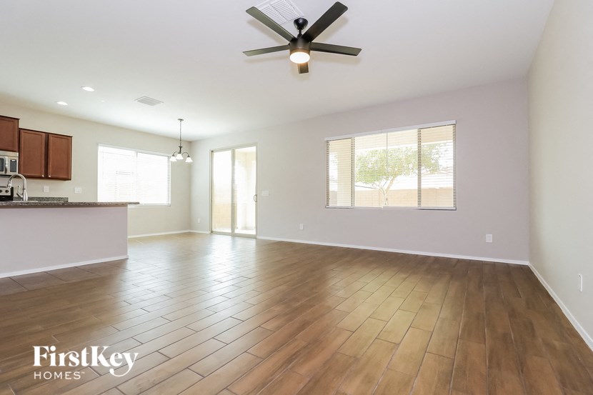 an empty living room and kitchen with a ceiling fan