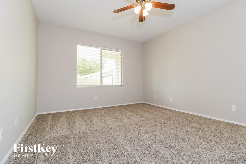 an empty living room with a ceiling fan and a window