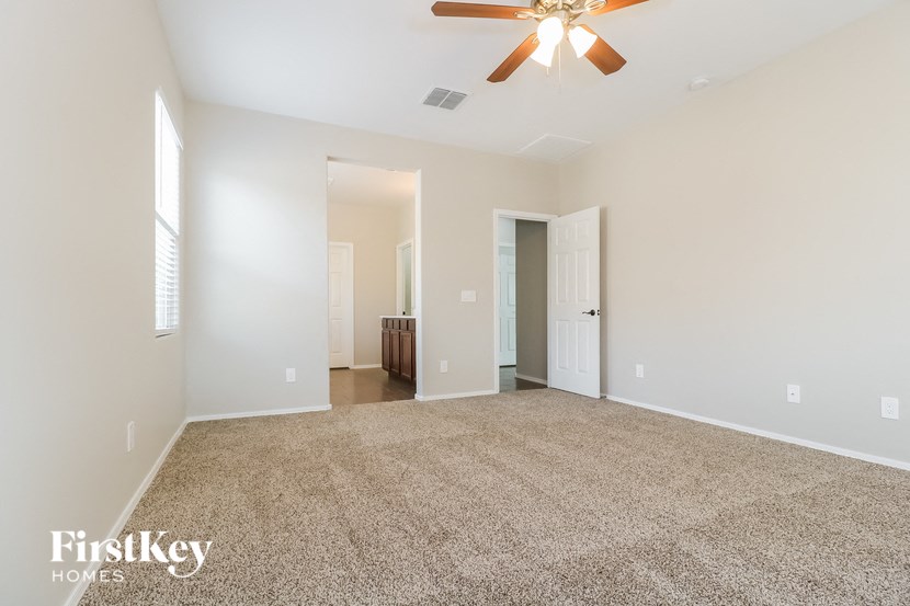an empty living room with a ceiling fan and white walls