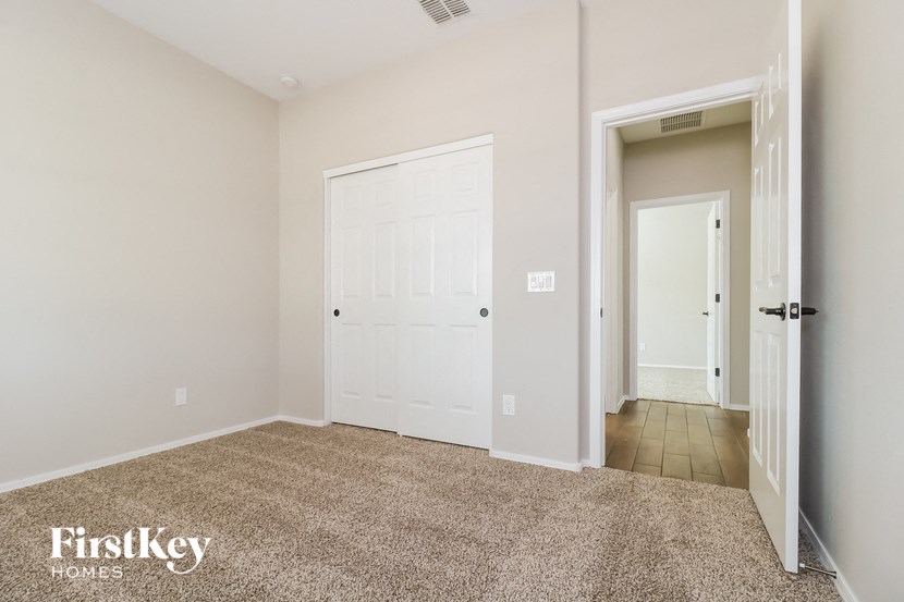 a bedroom with a white door and a hallway to a closet