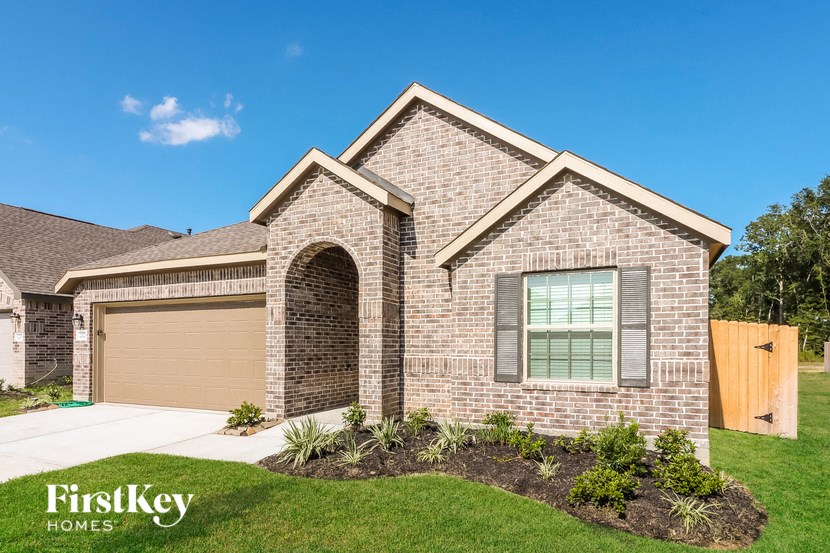 a brick house with a garage door and a lawn