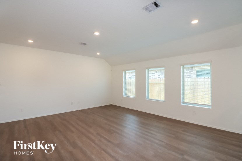 the spacious living room with wood floors and white walls