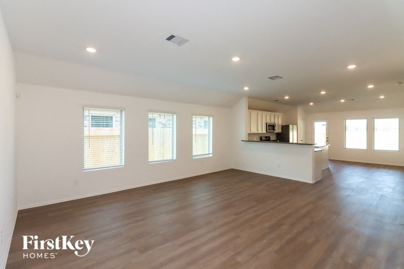 an empty living room with wood floors and a kitchen