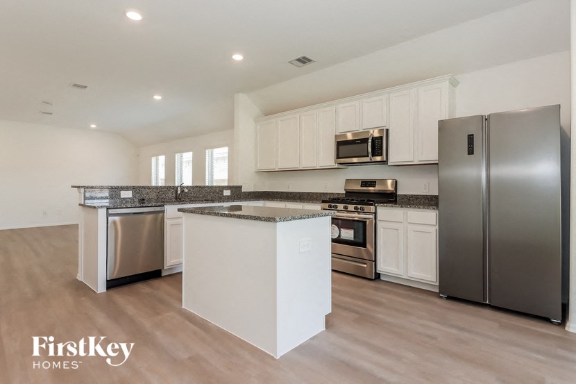 a large kitchen with stainless steel appliances and white cabinets