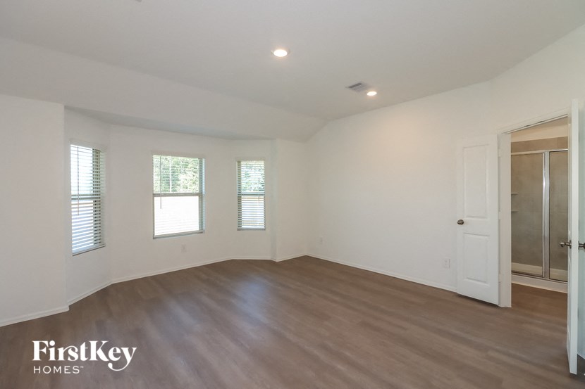 a bedroom with white walls and wood flooring and a closet