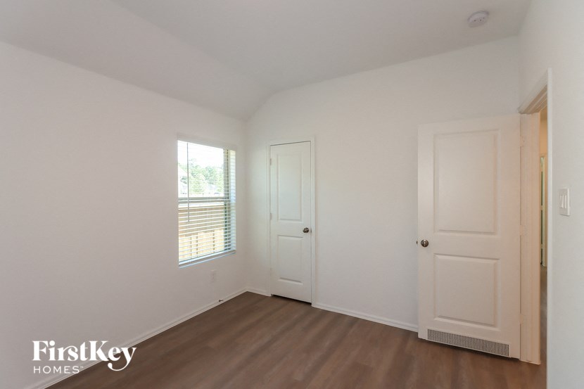 a bedroom with white walls and wooden floors and a white door