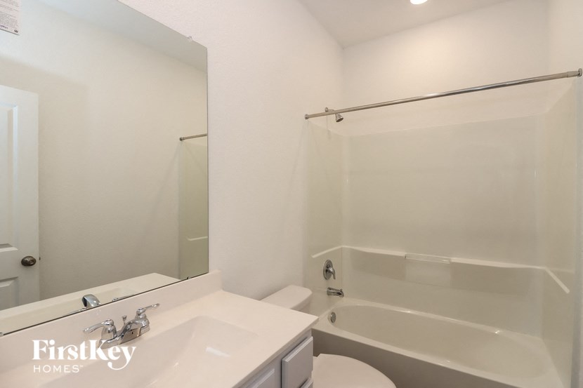 a white bathroom with a tub and a sink and a mirror