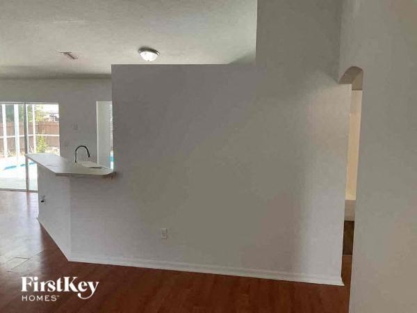 an empty living room with white walls and a kitchen