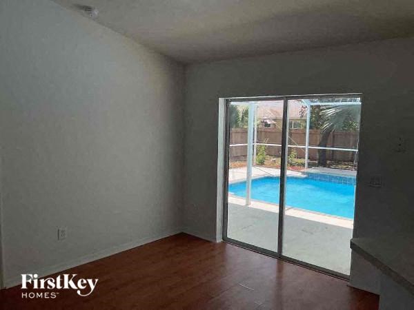 an empty living room with a sliding glass door to a pool