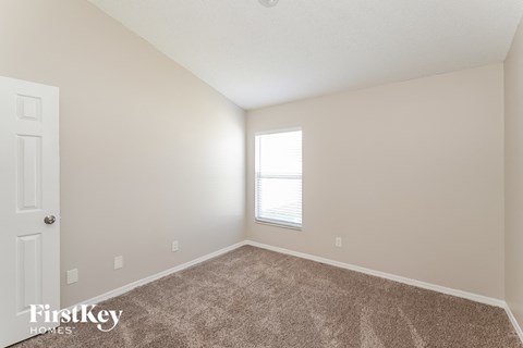 a spacious bedroom with carpeted flooring and a window