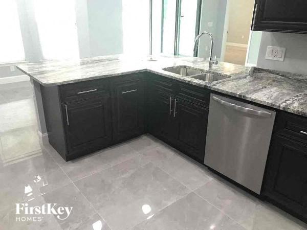 a kitchen with black cabinets and a stainless steel sink